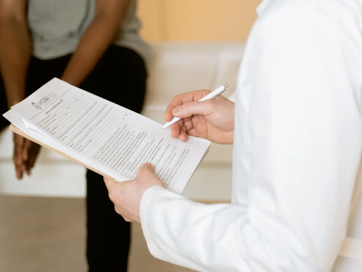 Hands holding a clipboard and pen during a discussion